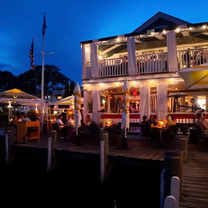 Evening on the water in Edgartown, out by the Atlantic. Lights on, tables full, boats tied up right...