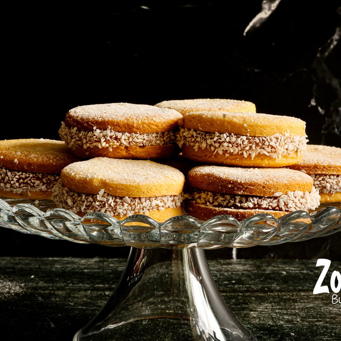 Alfajores Een heerlijk bros en kruimelig koekje met daartussen een royale laag romige dulce de leche en omhuld met wat kokosrasp.