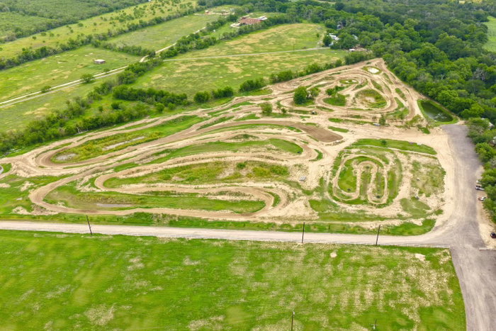 An aerial view of the winding dirt tracks and green fields at Creekside MX